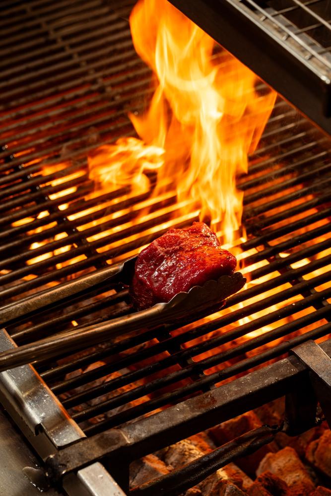 A steak lifted over the flames