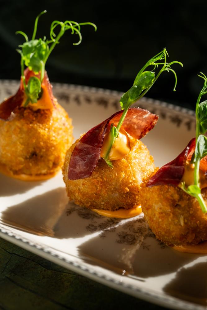 Croquetas topped with jamón and pea shoots