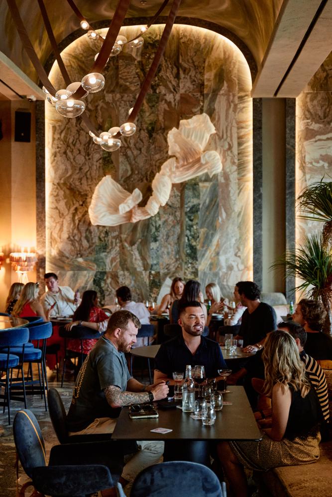 Guests dining beneath the backlit marble wall