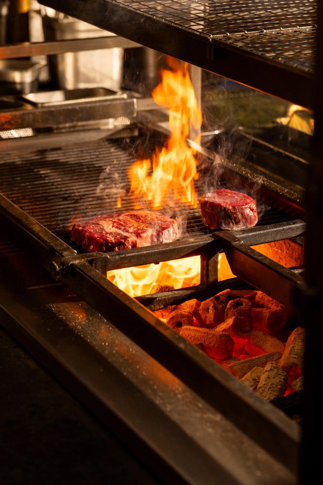 Steaks over flames and glowing coals